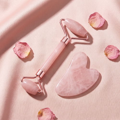 Revonae Glaé rose quartz roller and heart gua sha on blush satin with rose petals
